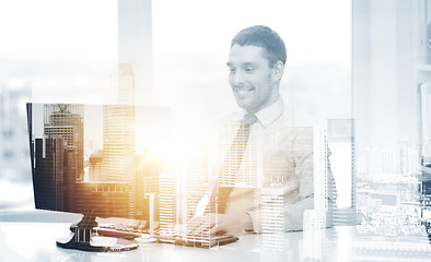 Image showing smiling businessman with computer at office