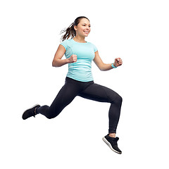 Image showing happy smiling sporty young woman jumping in air