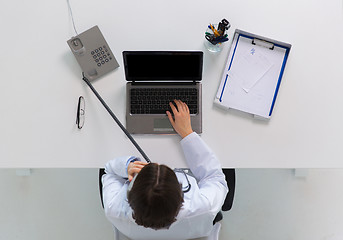 Image showing doctor with laptop calling on phone at clinic