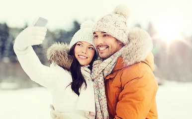Image showing happy couple taking selfie by smartphone in winter