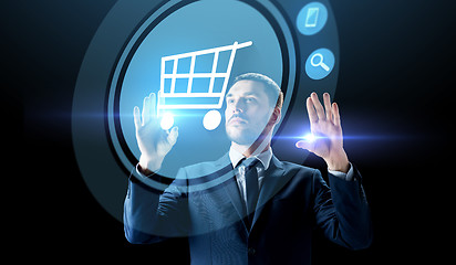 Image showing businessman with shopping cart on virtual screen