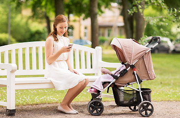 Image showing happy mother with smartphone and stroller at park