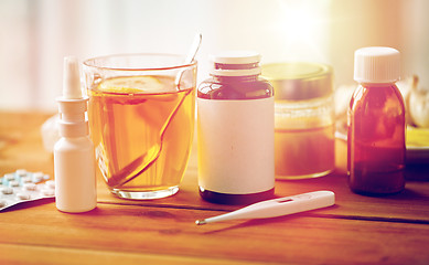 Image showing drugs, thermometer, honey and cup of tea on wood