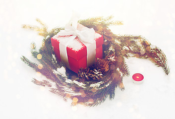 Image showing christmas gift and fir wreath with cones on snow