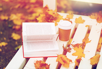 Image showing open book and coffee cup on bench in autumn park