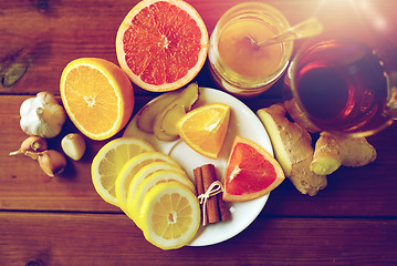 Image showing ginger tea with honey, citrus and garlic on wood