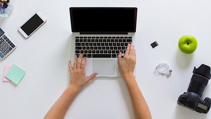 Image showing woman with camera working on laptop at table