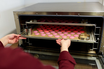 Image showing chef with macarons on oven tray at confectionery