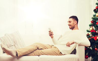 Image showing smiling man with smartphone at home for christmas