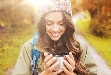 Image showing smiling young woman with cup and backpack hiking