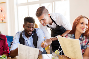 Image showing waiter and friends with menu and drinks at bar