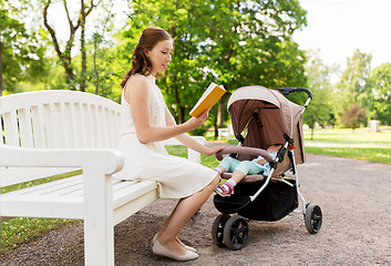 Image showing mother with child in stroller reading book at park