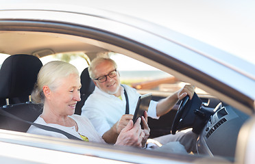 Image showing happy senior couple with tablet pc driving in car