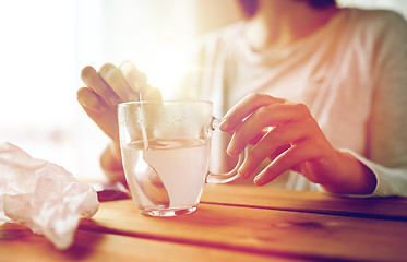 Image showing woman stirring medication in cup with spoon