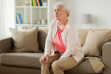 Image showing senior woman suffering from pain in leg at home