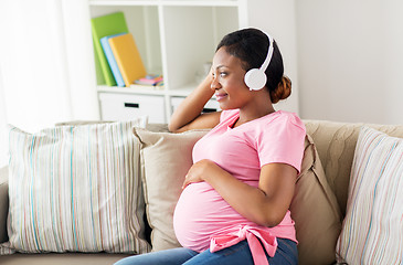 Image showing pregnant woman in headphones at home