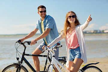 Image showing happy young couple riding bicycles at seaside