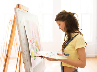 Image showing student girl with easel painting at art school