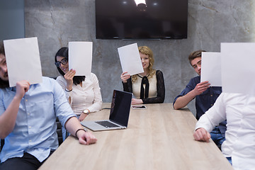 Image showing startup business team holding a white paper over face