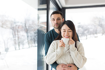 Image showing multiethnic couple enjoying morning coffee by the window