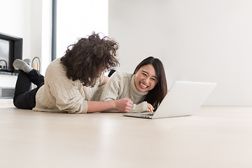 Image showing young multiethnic couple using a laptop on the floor