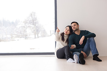 Image showing multiethnic couple sitting on the floor near window at home