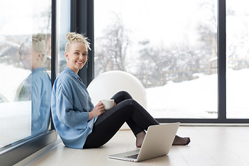 Image showing woman drinking coffee and using laptop at home