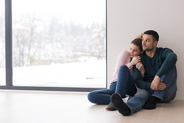 Image showing young couple sitting on the floor near window at home