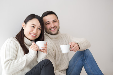 Image showing multiethnic couple enjoying morning coffee by the window