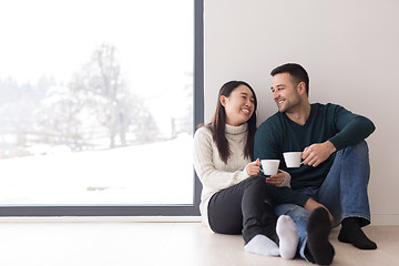 Image showing multiethnic couple enjoying morning coffee by the window