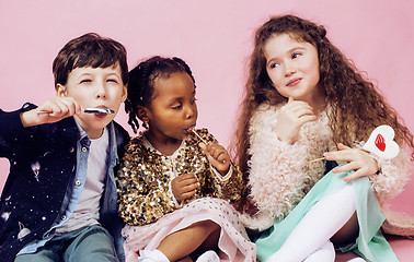 Image showing lifestyle people concept: diverse nation children playing together, caucasian boy with african little girl holding candy happy smiling