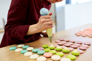 Image showing chef with injector squeezing filling to macarons