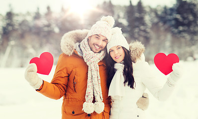 Image showing happy couple with red hearts over winter landscape