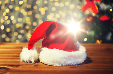 Image showing close up of santa hat on wooden table over lights