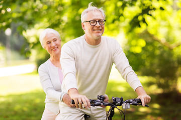 Image showing happy senior couple riding bicycle at park