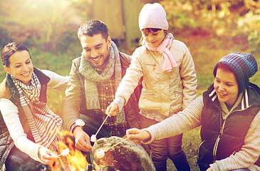 Image showing happy family roasting marshmallow over campfire