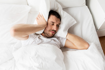 Image showing man in bed with pillow suffering from noise