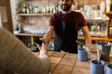 Image showing man with payment terminal and hand with smartphone