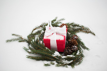 Image showing christmas gift and fir wreath with cones on snow