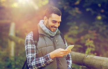 Image showing happy man with backpack and smartphone outdoors