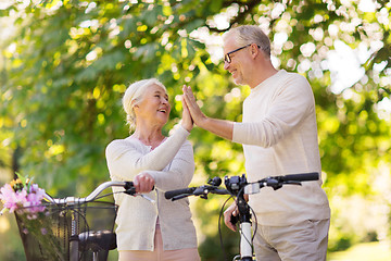 Image showing senior couple with bikes making high five at park