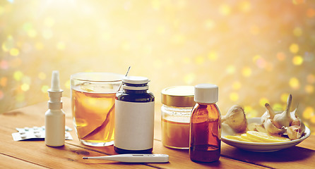 Image showing drugs, thermometer, honey and cup of tea on wood