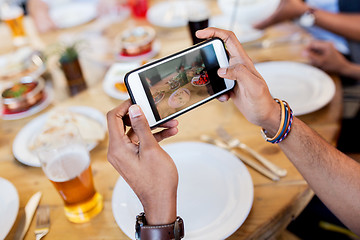 Image showing hands with smartphone picturing food at restaurant