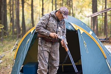 Image showing hunter loading shotgun in the hunting camp