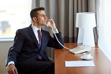 Image showing businessman calling on desk phone at hotel room