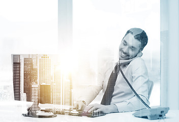 Image showing businessman with computer calling phone at office