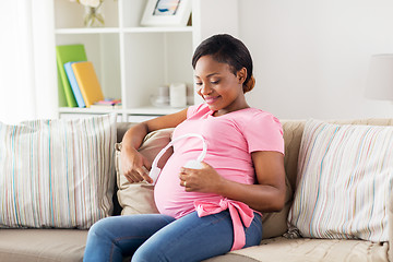 Image showing pregnant woman with headphones at home