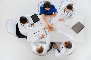 Image showing group of doctors holding hands together at table