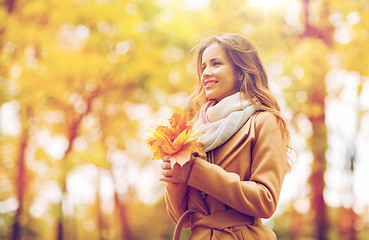 Image showing beautiful woman with maple leaves in autumn park