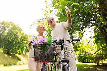 Image showing senior couple with bicycles taking selfie at park